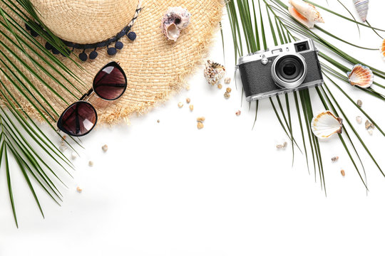 Flat lay composition with stylish hat, camera and beach objects on white background