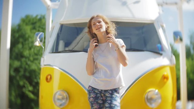 young woman outdoors by yellow vagon car listening music in headphones using smartphone - relaxing, enjoying, concept of technology and travel
