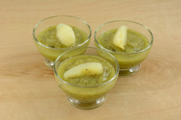 Kiwi fruit puree dessert in glass cups with pear slices as healthy cool refreshment on hot summer