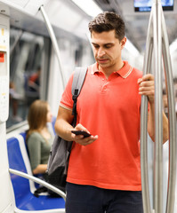Male is traveling and standing with mobile in the train