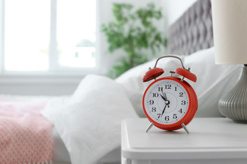 Analog alarm clock on table in bedroom. Time of day