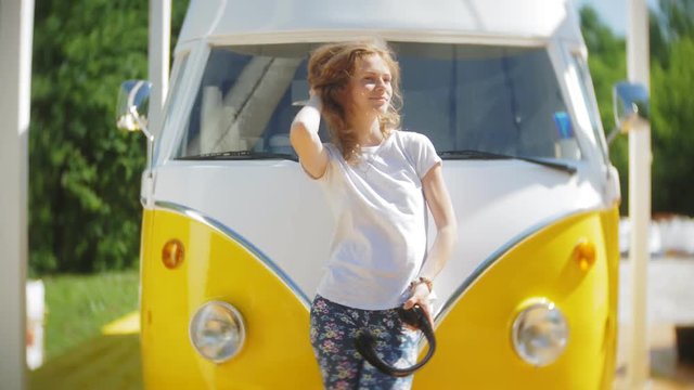 young woman outdoors by yellow vagon car listening music in headphones using smartphone - relaxing, enjoying, concept of technology and travel