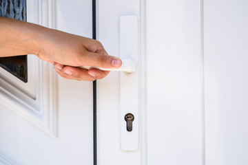 Naklejka premium front door. hand holds doorknob on front door PVC