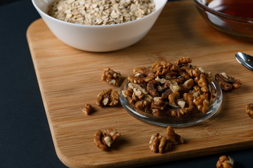 Healthy Breakfast ingredients: honey, walnuts, oatmeal on a dark background. Healthy diet. Close up.