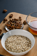 Healthy Breakfast ingredients: honey, walnuts, oatmeal on a dark background. Healthy diet. Close up.