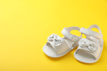 Pair of cute baby sandals on color background