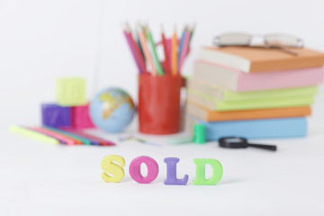 word sold on blurred background of school supplies .photo with copy space