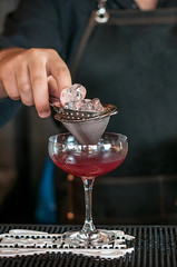 bartender barmen with cocktail preparing red cocktail at bar. alcohol drinks, job people and luxury night club concept