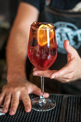 bartender barmen with cocktail preparing orange cocktail at bar. alcohol drinks, job people and luxury night club concept