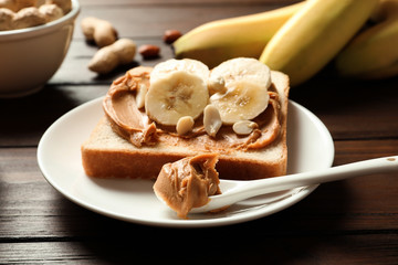 Toast bread with peanut butter and banana slices on wooden table, closeup