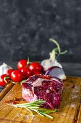 Raw marbled beef meet steak rib eye. Beef steak on the wooden plate with the rosemary and tomatoes