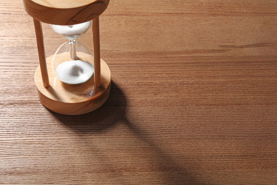 Hourglass with flowing sand on wooden background. Time management