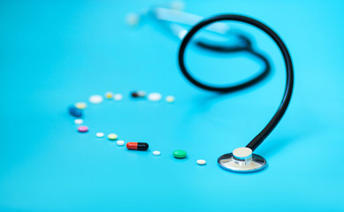 Medicine stethoscope and pills on blue background. Cardiology heart treatment.