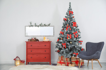 Decorated Christmas tree and armchair in stylish living room interior
