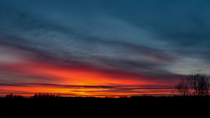 dramatic sunrise over the calm country side trees