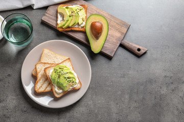 Flat lay composition with toasted bread and avocado on grey background