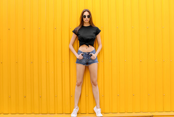 Young woman wearing black t-shirt near color wall on street