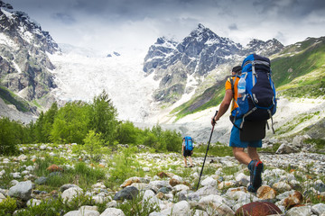 Climbers with hiking backpacks go to the mountain. hikers in mountains. Tourists hike on rocky...
