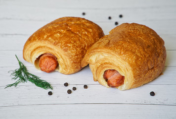 Two hot dogs made from puff pastry lie on a white surface