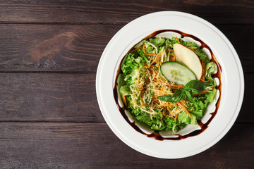 Plate with delicious fresh salad on table, top view