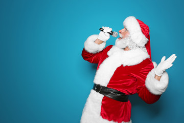 Santa Claus singing into microphone on color background. Christmas music