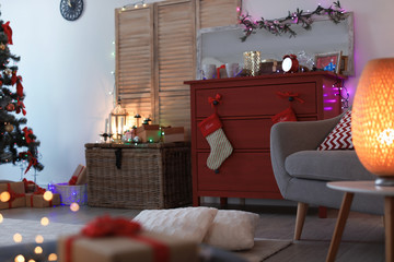 Chest of drawers with red Christmas stockings in stylish interior