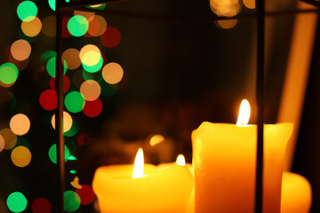 Burning candles against blurred Christmas lights