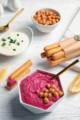 Ceramic bowl with tasty beet hummus on light table
