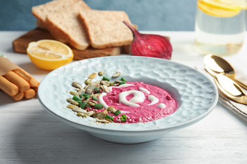 Plate with fresh beet hummus and seeds on wooden table