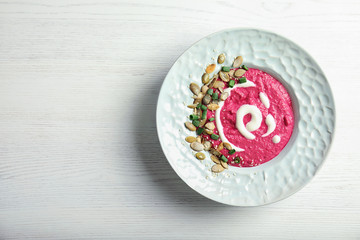 Plate with fresh beet hummus and seeds on wooden background