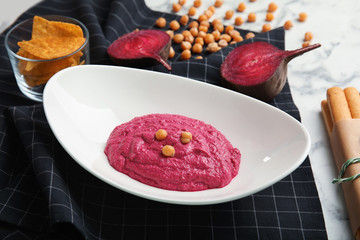 Plate with tasty beet hummus and napkin on marble table