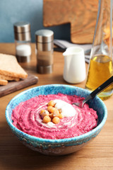 Bowl with tasty creamy beet hummus on wooden table