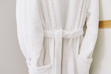 Pure white comfy cotton bathrobes on hangers. Concept of coziness and comfort. Relaxing at home or in a hotel.