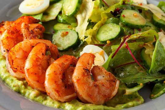 Delicious grilled shrimps served with salad with green vegetables - lettuce, cucumber
