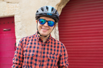 Funny man at helmet and sunglasses giving a thumbs up on red outdoor background