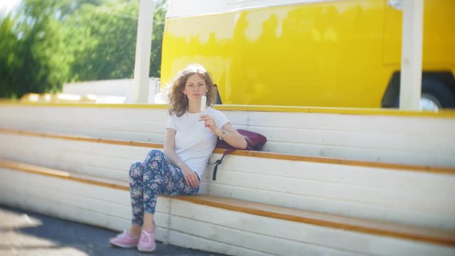 young woman outdoors by yellow vagon car listening music in headphones using smartphone - relaxing, enjoying, concept of technology and travel