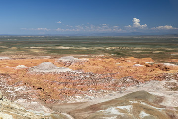 Aerial view on multicolored red, orange and yellow striped hills under the bright blue sky in Kiin-Kerysh (Valley of Spirits) Eastern Kazakhstan