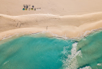 Fototapeta na wymiar Top view of beautiful beach. Aerial drone shot of turquoise sea water at the beach - space for text. Caribbean seaside beach with turquoise water and big waves aerial view. Cancun beach aerial view. 