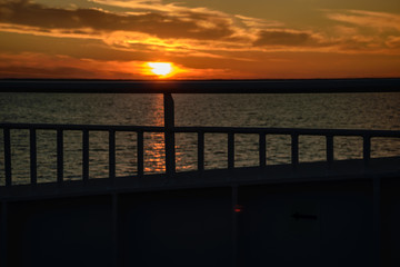 Obraz premium dramatic sunrise over the baltic sea seen through ships ropes and metal railings