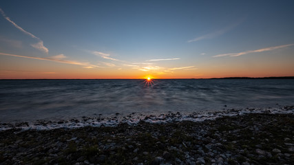 dramatic sunrise over the baltic sea with rocky beach and trees on the shore