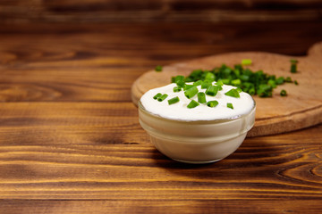 Sour cream and green onion on wooden table