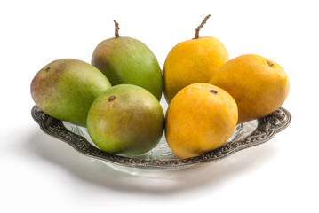 Raw and ripe mangoes in glass plate