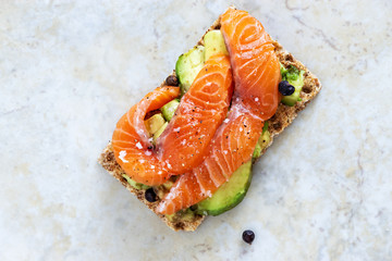 Crisp sandwiches with avocado and salmon. Marble background. Selective focus. Copy space. Top view.