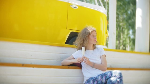 young woman outdoors by yellow vagon car listening music in headphones using smartphone - relaxing, enjoying, concept of technology and travel