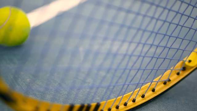 Close up of tennis equipment on the court. Sport, recreation concept. Yellow racket with a tennis ball in motion on a clay green blue court next to the white line with copy space and soft focus.