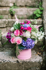beautiful flowers and greenery in a pink box on the background of vintage stone stairs