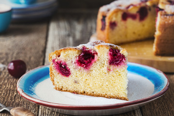 Slice of cherry cake and fresh summer berries on rustic table