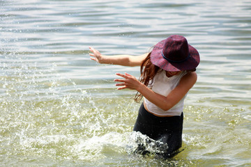 Beautiful slim Asian girl playing in water at the sea coast