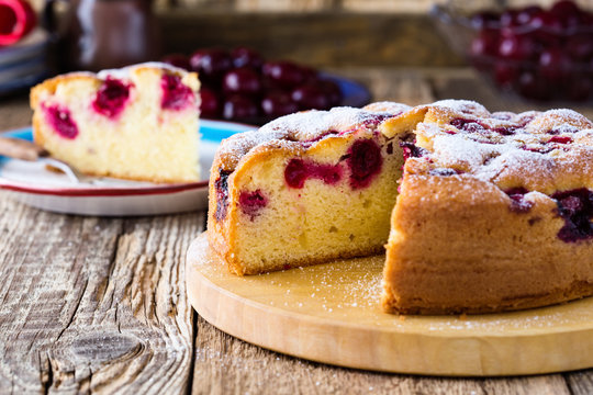 Cherry cake and slice of cake on rustic table