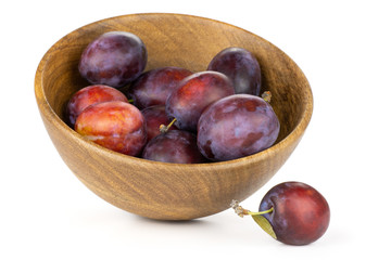 Obraz premium Lot of whole fresh violet-blue plum vibrant moyer variety in a wooden bowl isolated on white